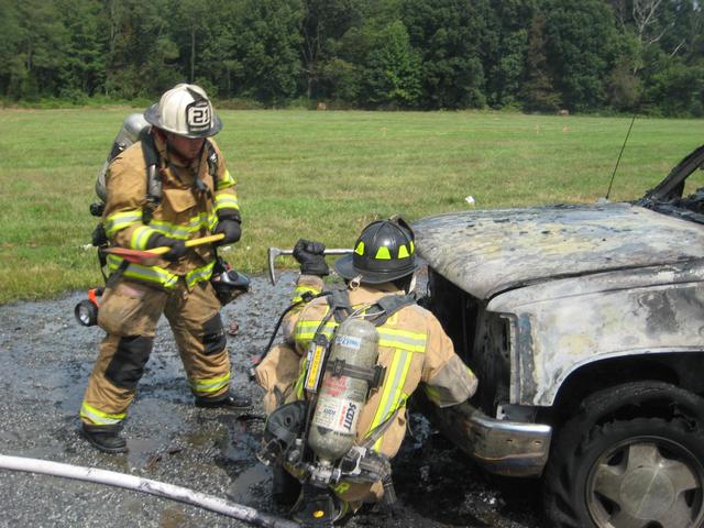 Lieutenant Brian Slauch and Firefighter Bill Hirthler opening the hood at a car fire.